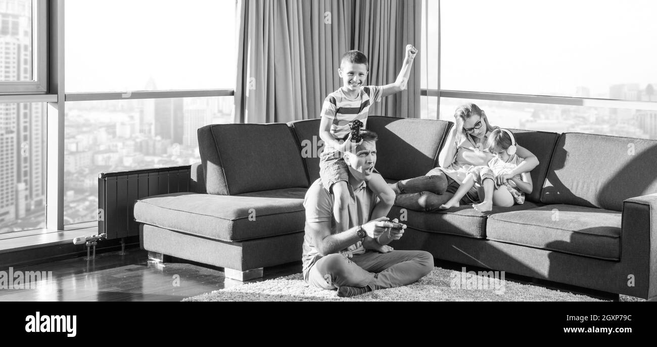 La famiglia felice. Padre, madre e figli la riproduzione di un video gioco di padre e figlio di giocare con i videogiochi insieme sul pavimento Foto Stock