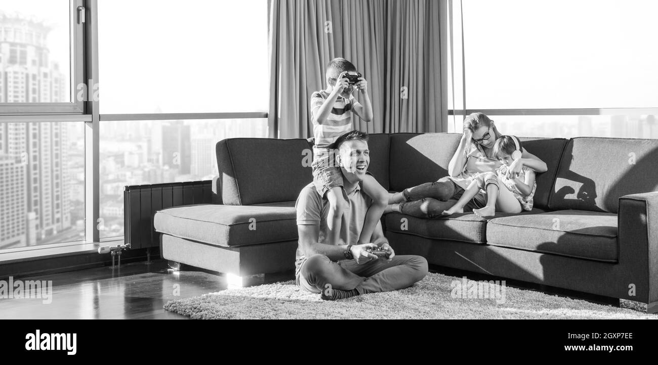 La famiglia felice. Padre, madre e figli la riproduzione di un video gioco di padre e figlio di giocare con i videogiochi insieme sul pavimento Foto Stock