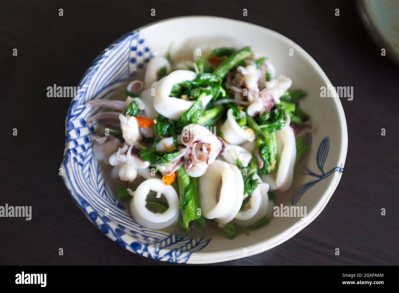 Il basilico fritto lascia il calamaro in una ciotola bianca Foto Stock