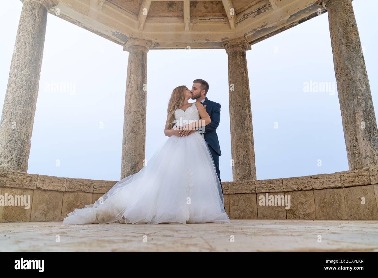 Coppia di nozze appena sposato baciare all'interno di un tempio Foto Stock