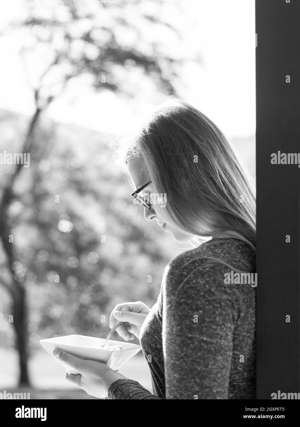 Giovane bella donna di successo di consumare la colazione nel vano della porta della sua casa di lusso villa Foto Stock