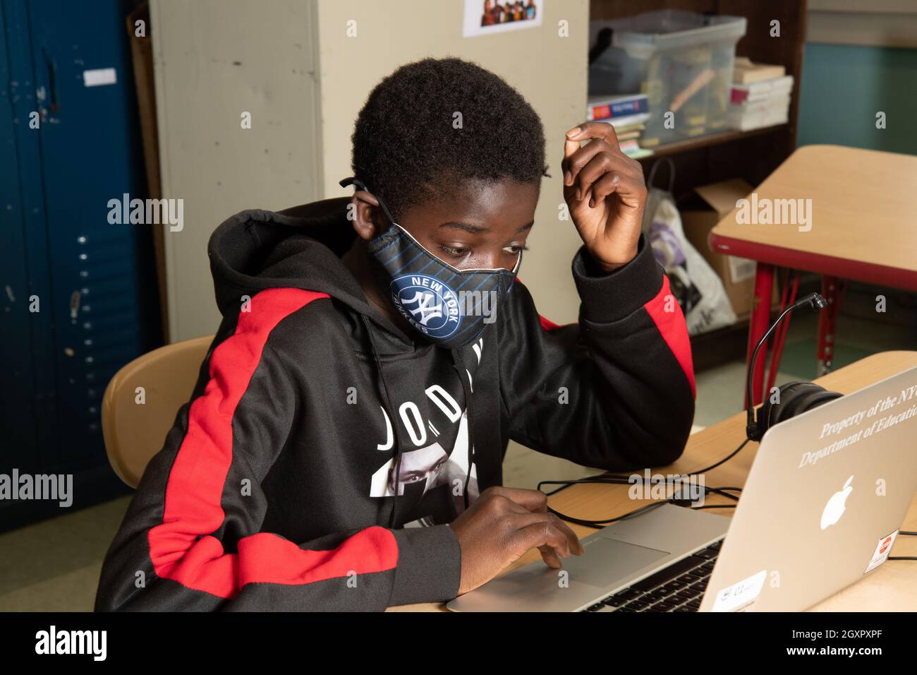 Istruzione studente maschile di scuola superiore in classe al lavoro su computer portatile, indossare maschera per proteggere contro l'infezione Covid-19 Foto Stock