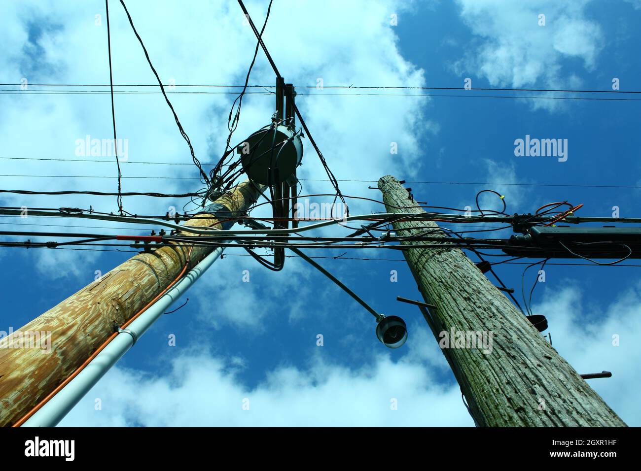Due poli telefonici contro un cielo blu ma nuvoloso Foto Stock