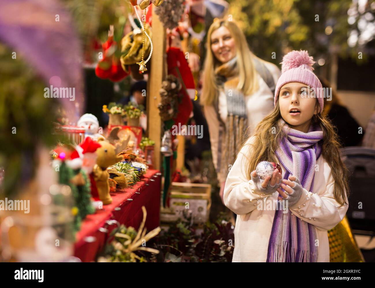 Ragazza entusiasta adolescente che sceglie le decorazioni dell'albero al mercato di strada Foto Stock