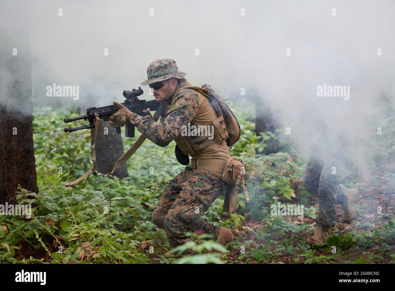 un moderno soldato di guerra in azione che punta all'arma ottica a vista laser in posizione di combattimento mentre cerca un bersaglio in battaglia Foto Stock