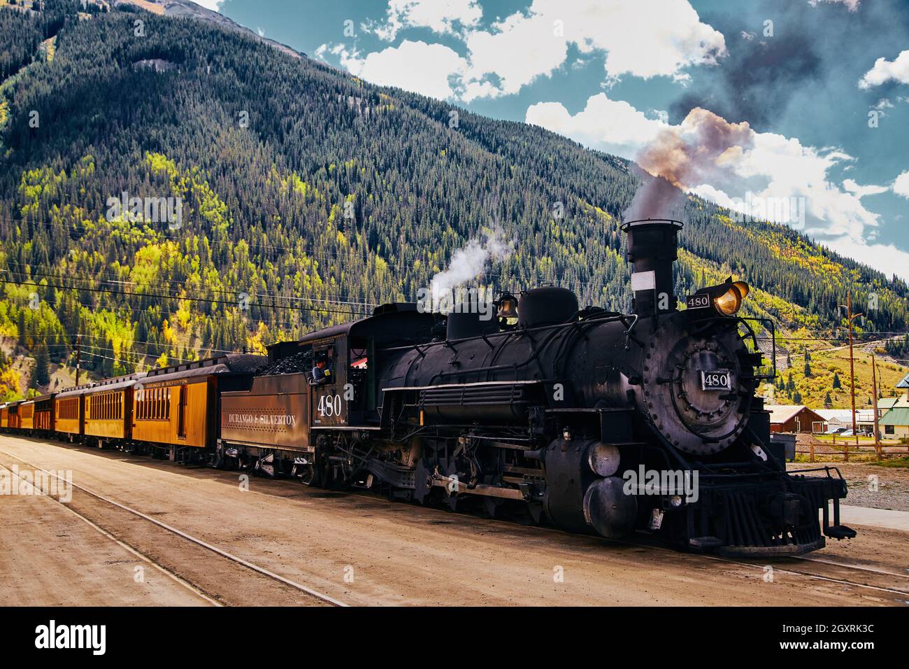 Treno di locomotiva vintage con montagne di alberi di caduta sullo sfondo Foto Stock