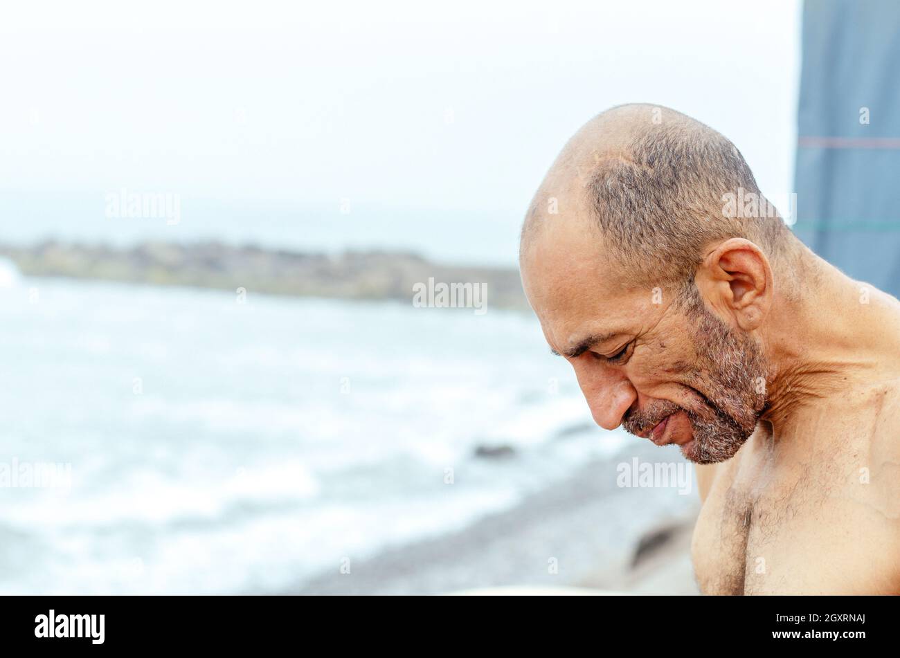 Ritratto di un anziano pensieroso che si rilassa sulla spiaggia Foto Stock