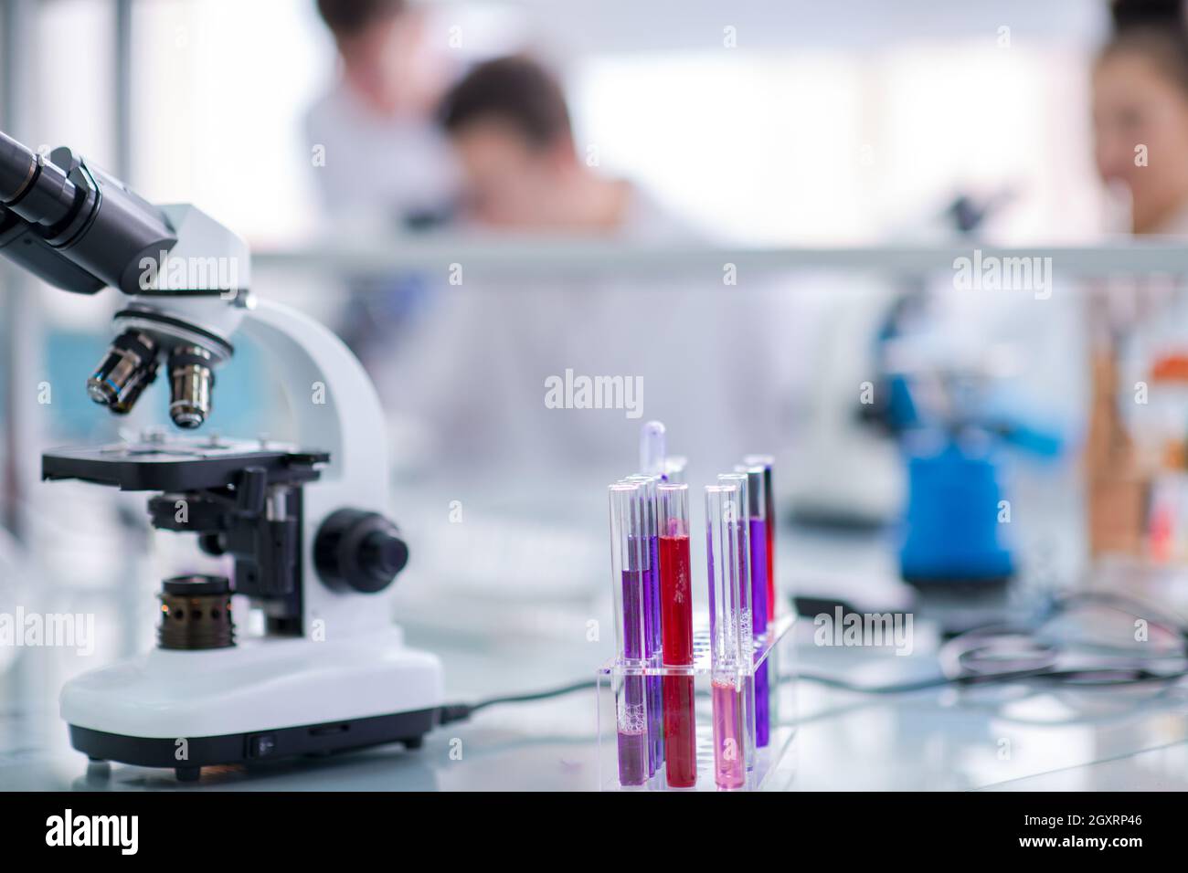 Microscopio sul luogo di lavoro nei pressi di provette con liquido diverso. Assistenza sanitaria e il concetto di biotecnologia Foto Stock