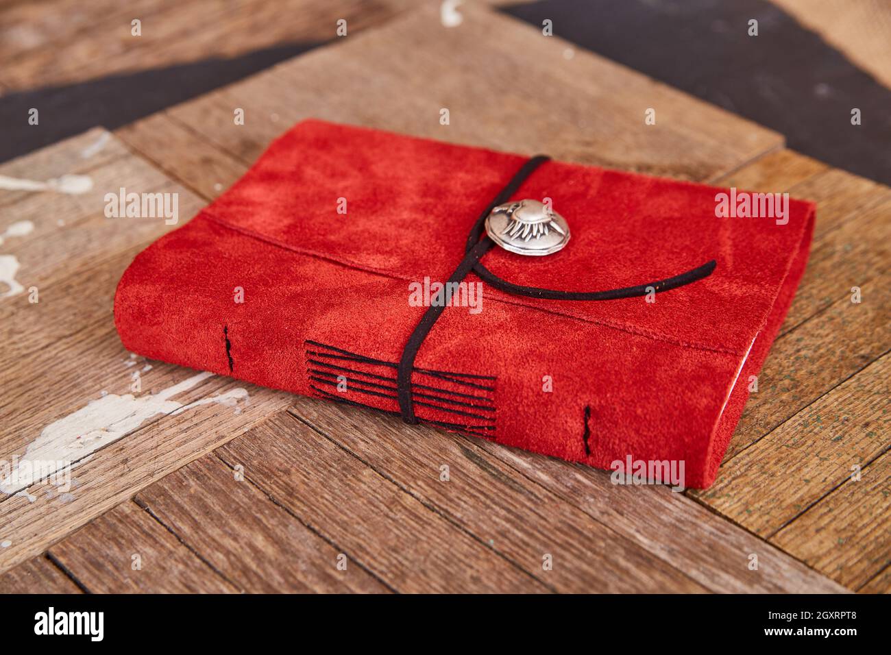 Libro in pelle rossa lavorato a mano con filo nero su assi in legno Foto Stock