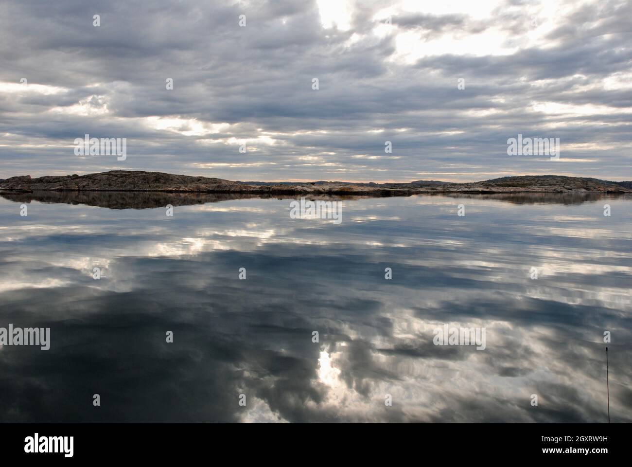 Riflessi delle nuvole sui mari tranquilli del mattino poco prima dell'alba nell'arcipelago di Fjällbacka, sulla costa occidentale della Svezia Foto Stock