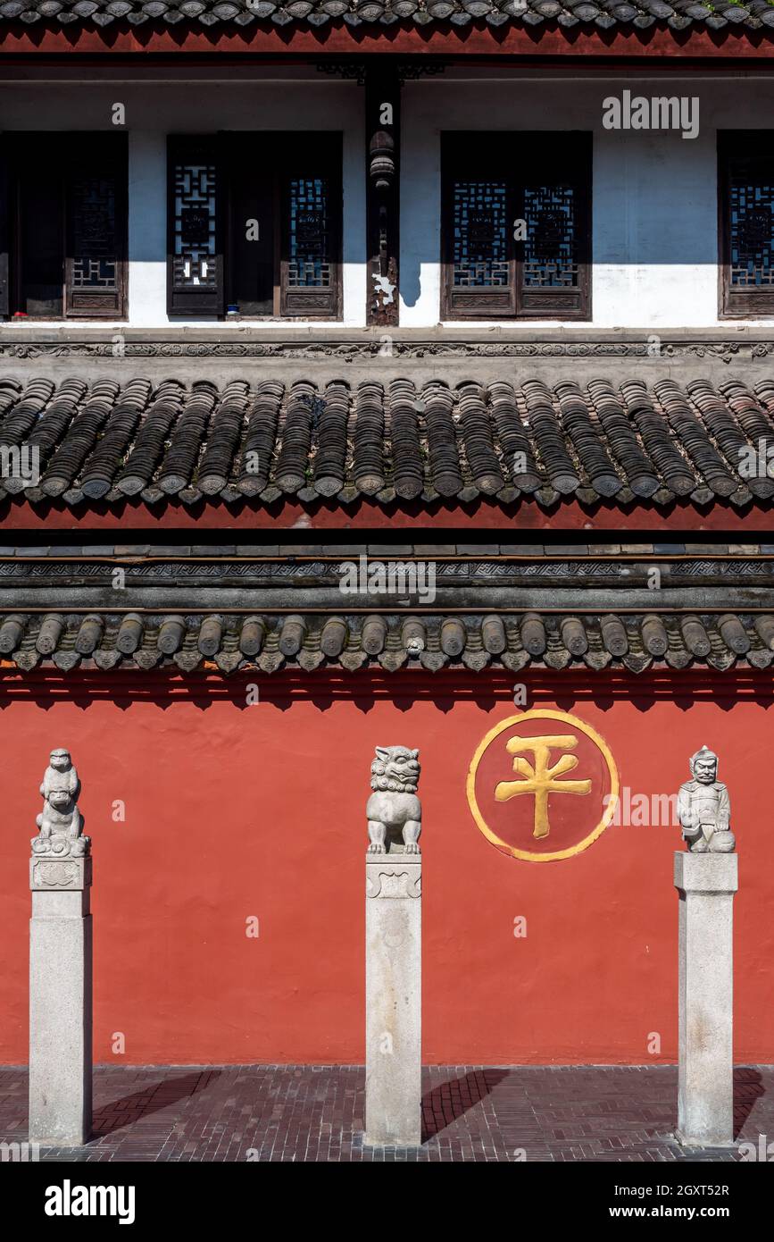 Chengdu, provincia di Sichuan, Cina - 28 settembre 2021 : tre statue di fronte alla parete rossa circostante del monastero buddista di Wenshu con il carattere cinese - ping- significa pace. Foto Stock