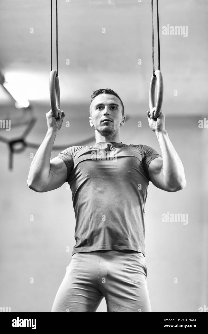 Fitness uomo bello fare immersione esercizio utilizzando anelli in palestra Foto Stock