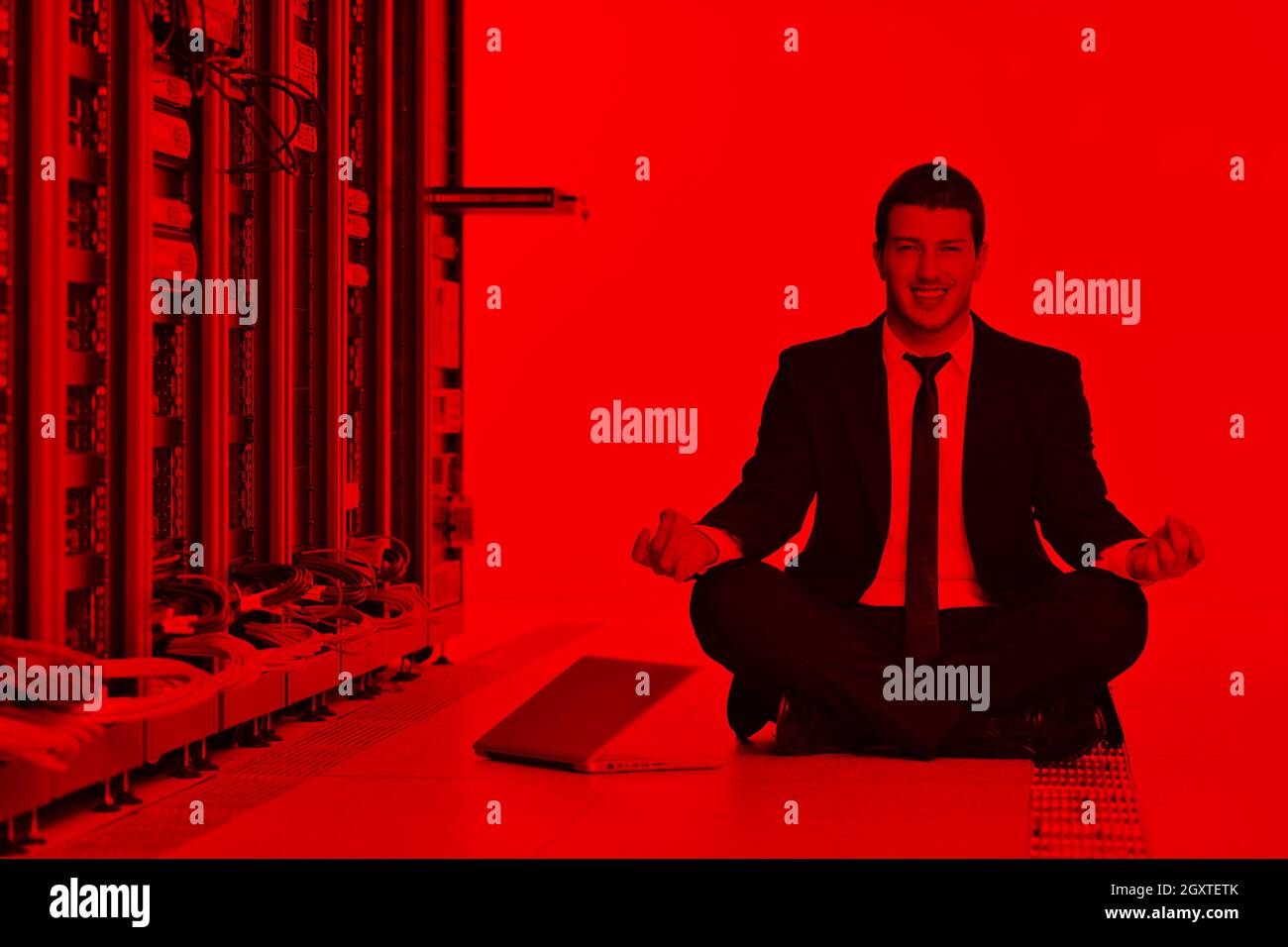 Bel giovane uomo d affari in abito nero e cravatta pratica yoga e relax al server di rete sala mentre in rappresentanza di stres concetto di controllo Foto Stock