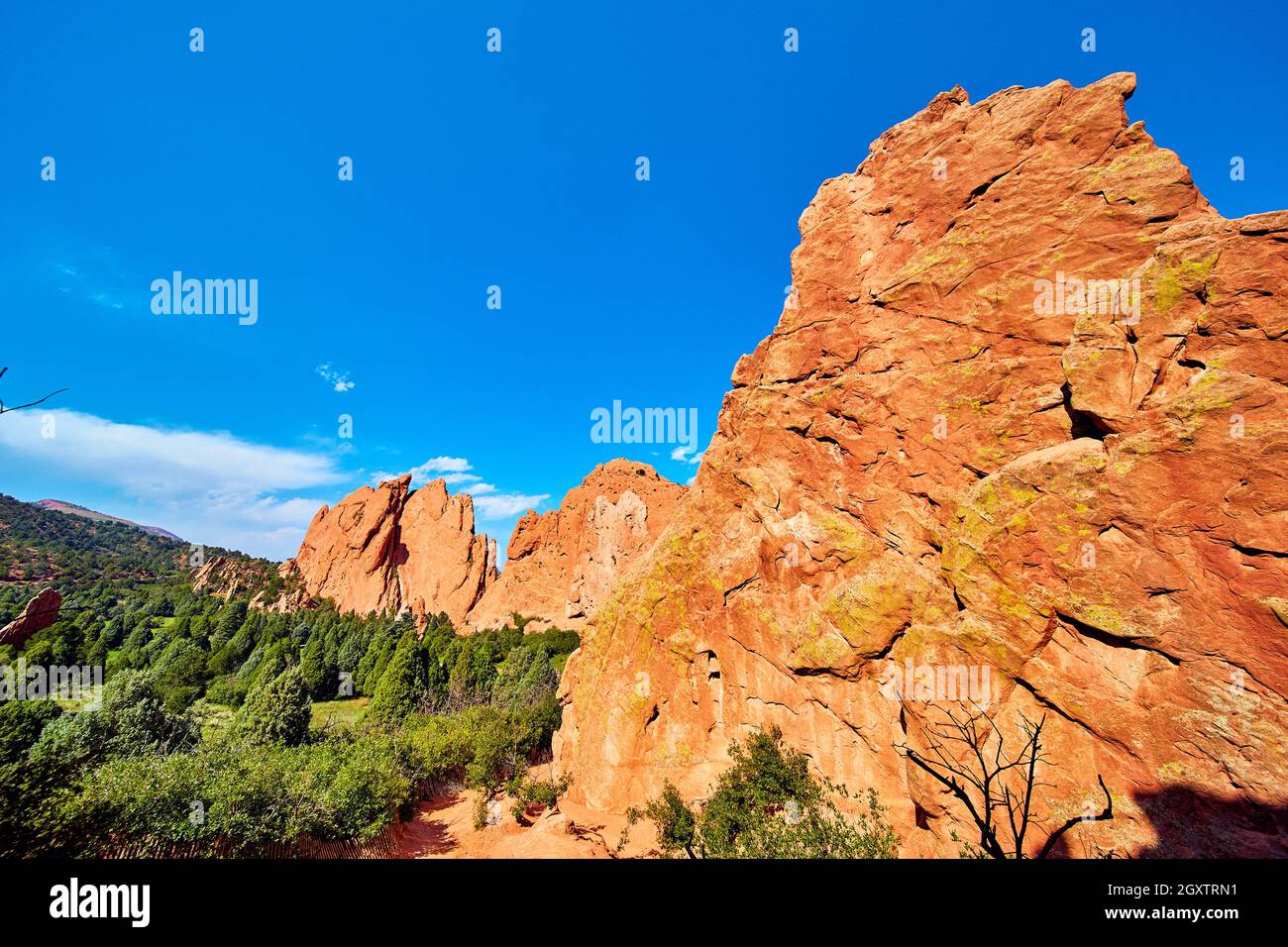 Mucchio di rocce rosse di montagna giganti in verde foresta con cielo blu Foto Stock