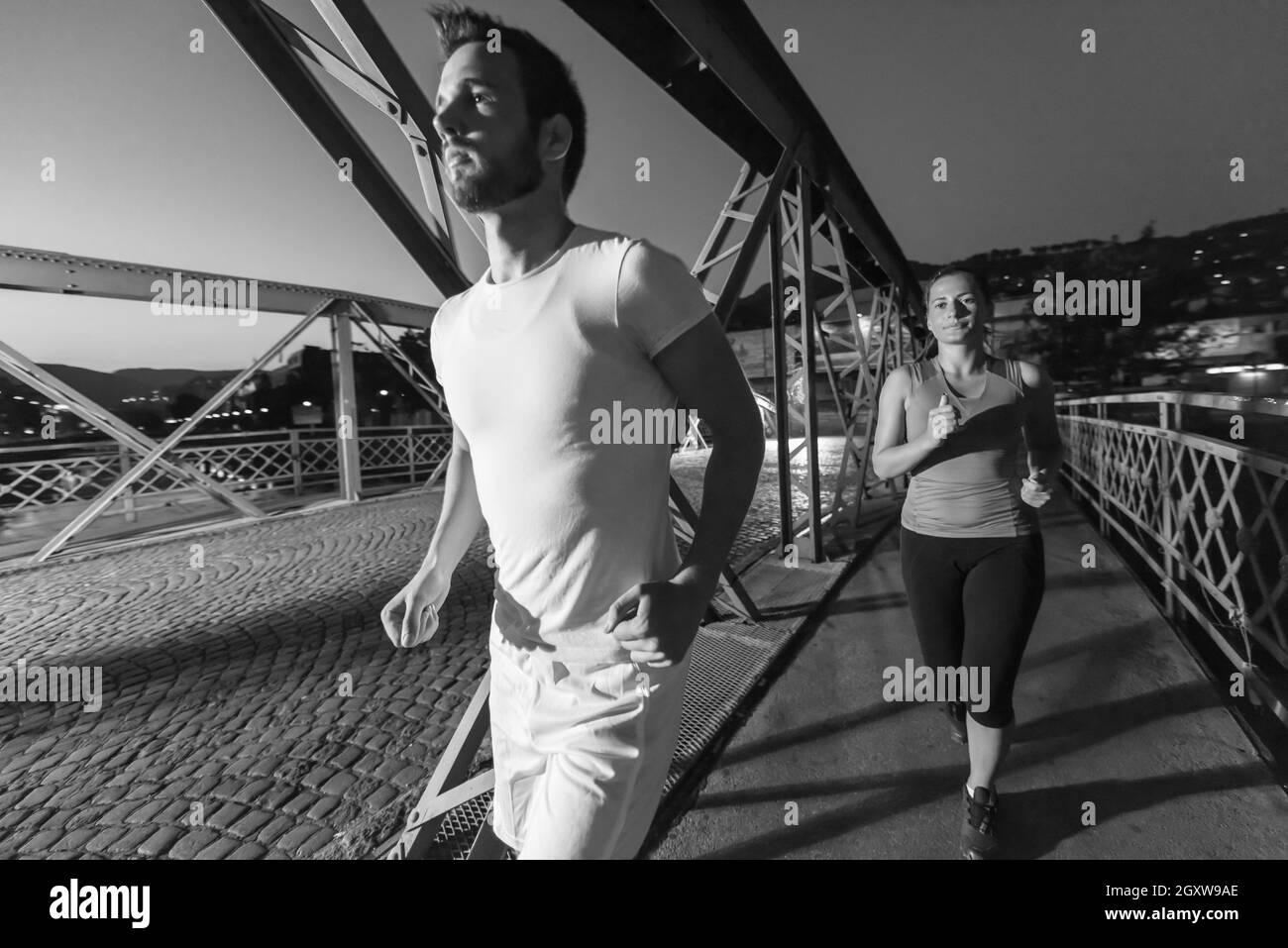 Urban sport, sano giovane jogging attraverso il ponte in città al mattino presto nella notte Foto Stock