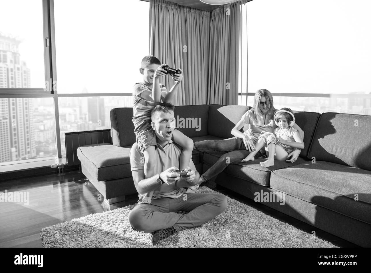 La famiglia felice. Padre, madre e figli la riproduzione di un video gioco di padre e figlio di giocare con i videogiochi insieme sul pavimento Foto Stock