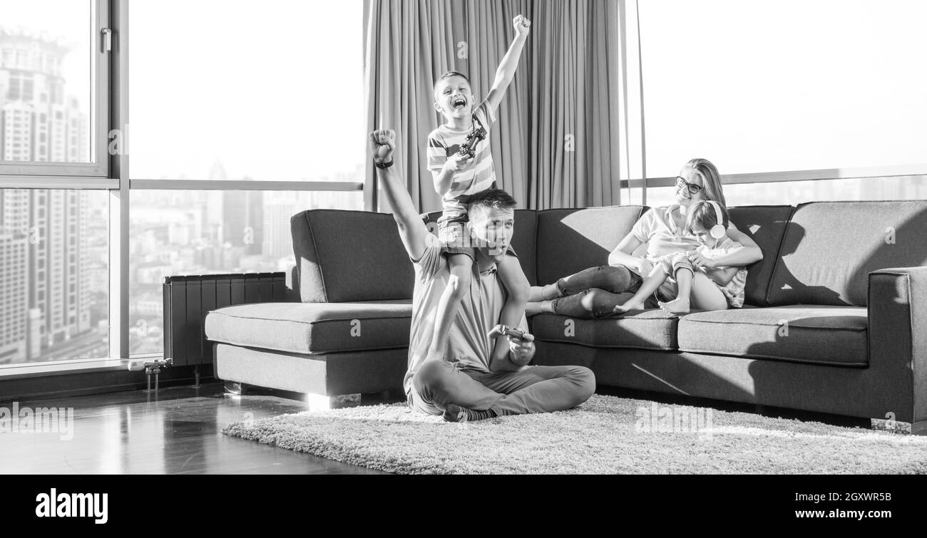 La famiglia felice. Padre, madre e figli la riproduzione di un video gioco di padre e figlio di giocare con i videogiochi insieme sul pavimento Foto Stock