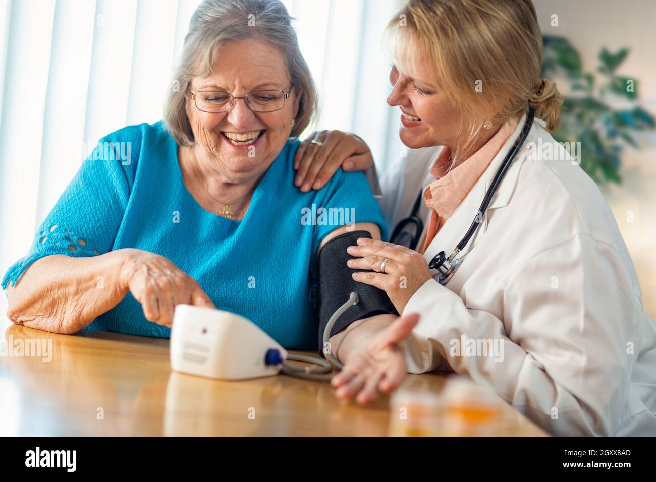 Senior donna adulta imparare dal medico donna di utilizzare la pressione sanguigna macchina. Foto Stock