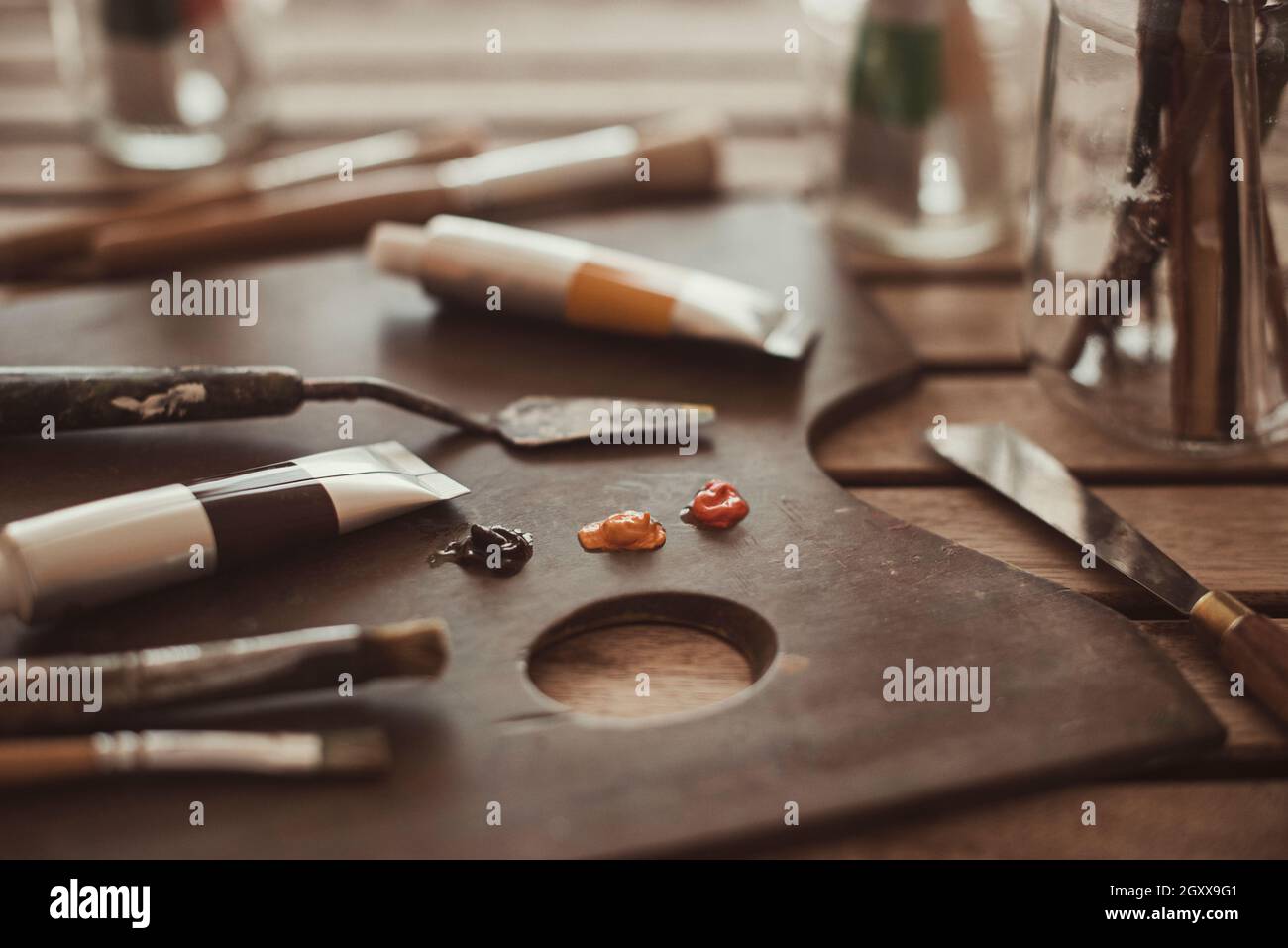 Oliare la vernice, i pennelli e i materiali di pittura su una tavolozza Foto Stock