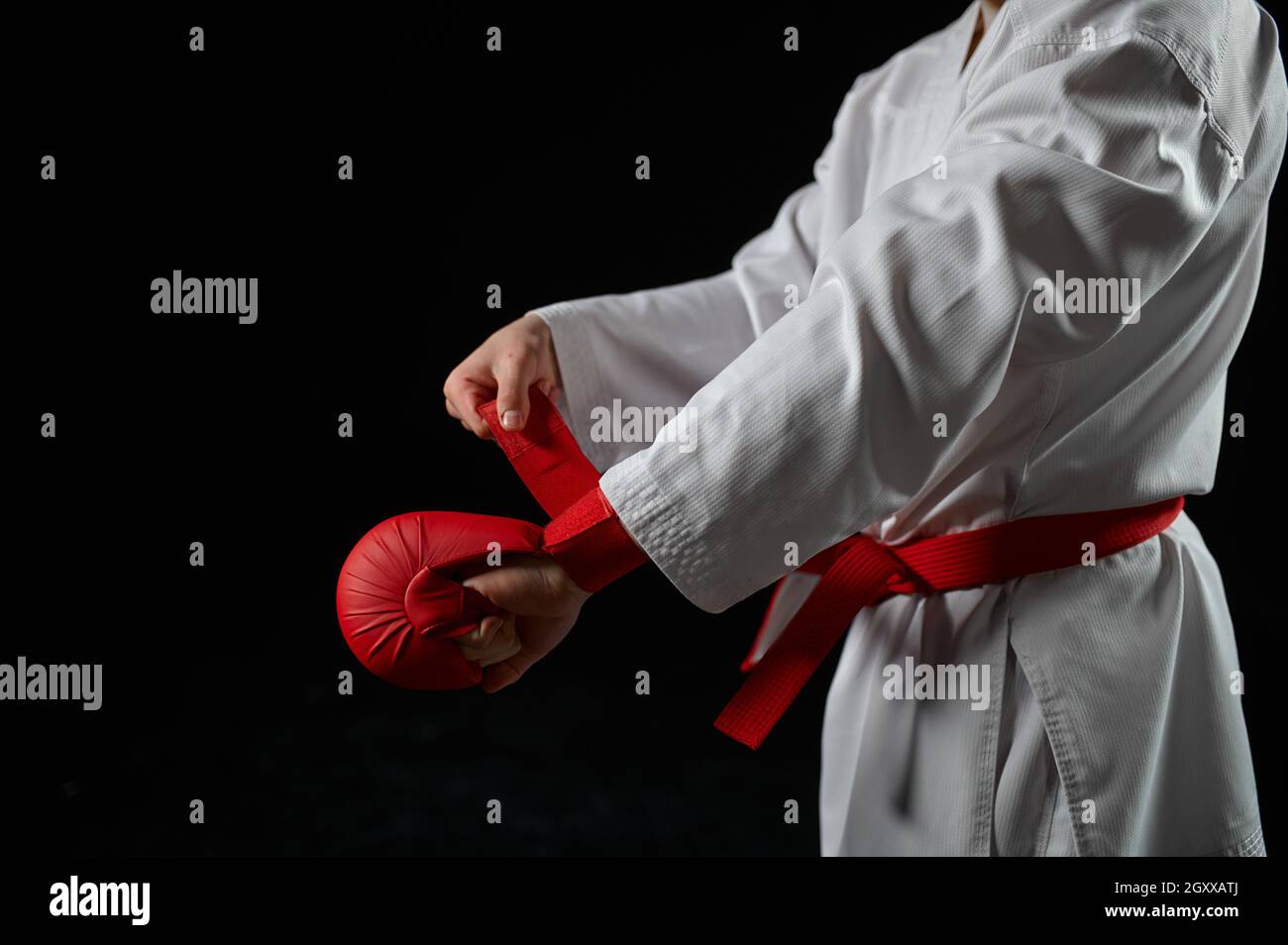 Caccia al karate maschile in kimono bianco con cintura rossa e guanti,  presa da combattimento, sfondo scuro. Carateka su allenamento, arti marziali,  allenamento prima di fig Foto stock - Alamy