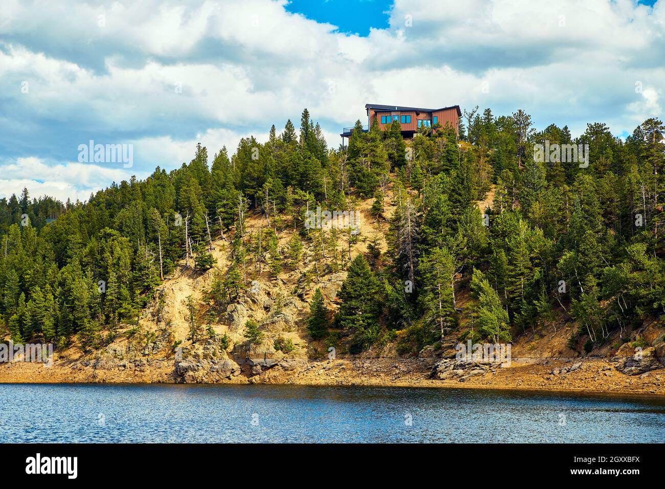 Casa in cima a una piccola montagna di pini accanto all'acqua Foto Stock