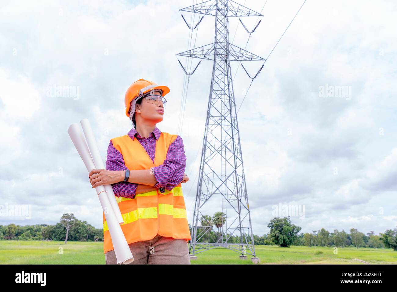 Donna ingegneri edili che controllano il layout su ipad o computer digitale. Il caposquadra lavora nel cantiere con sfondo della Torre elettrica. Foto Stock