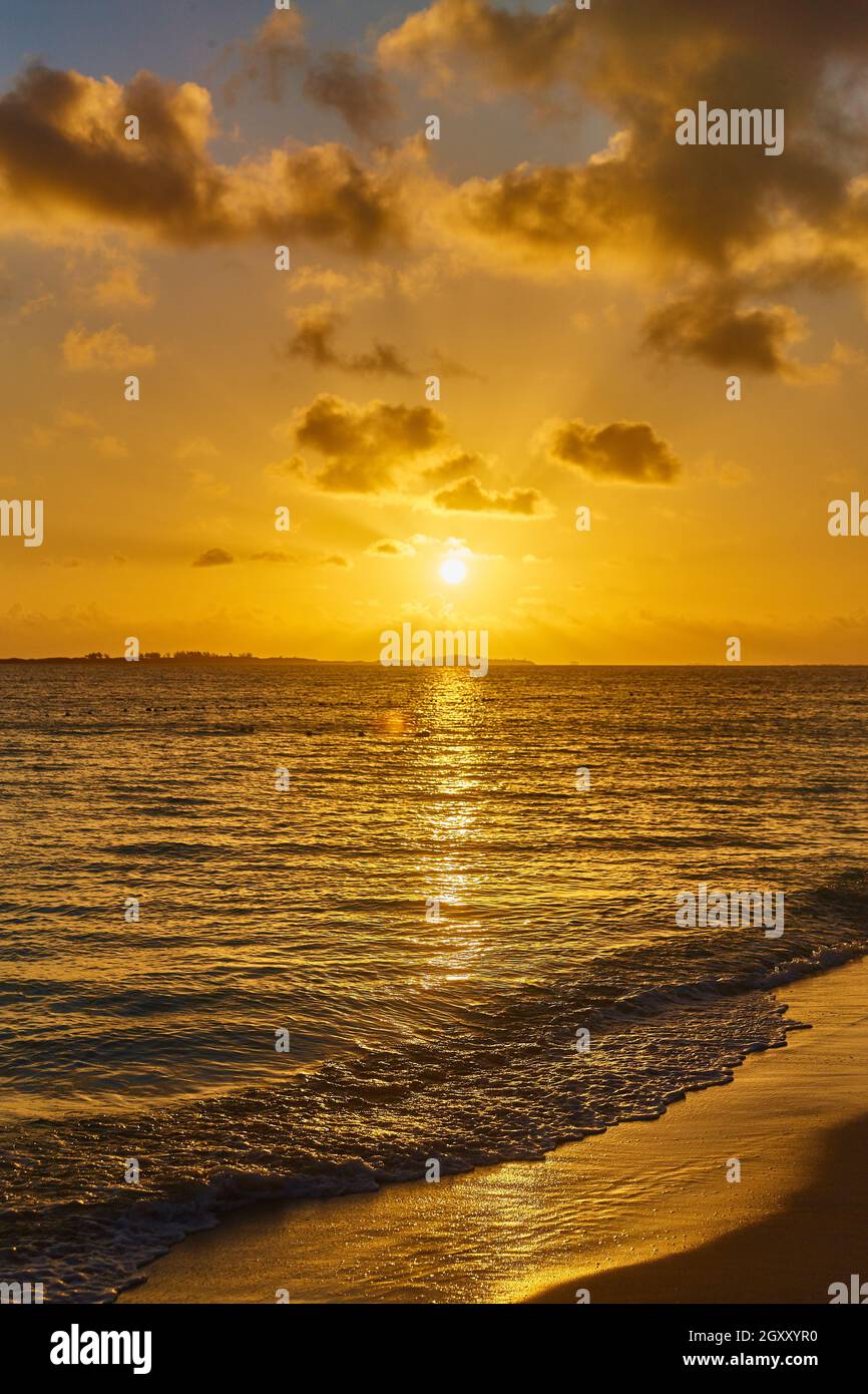Ora d'oro del tramonto con spiaggia sabbiosa e onde d'acqua dell'oceano Foto Stock