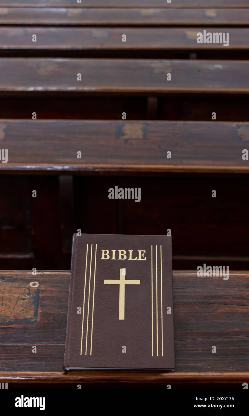 La Sacra Bibbia sulla tavola di una panchina di preghiera nella chiesa. Foto Stock