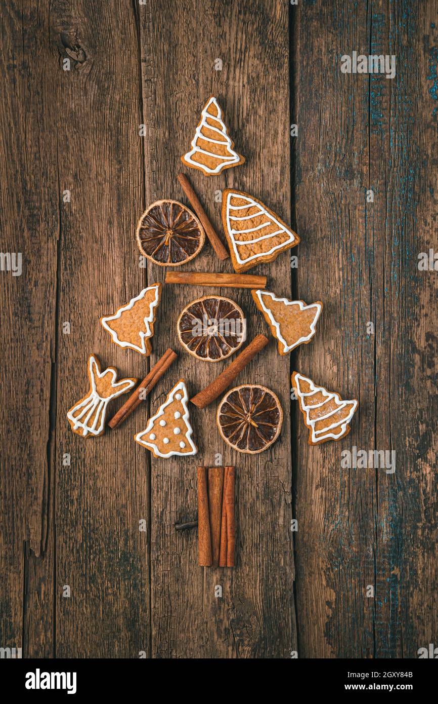 Albero di Natale fatto di pan di zenzero, cannella e limone su sfondo di legno. Vista dall'alto, verticale. Foto Stock