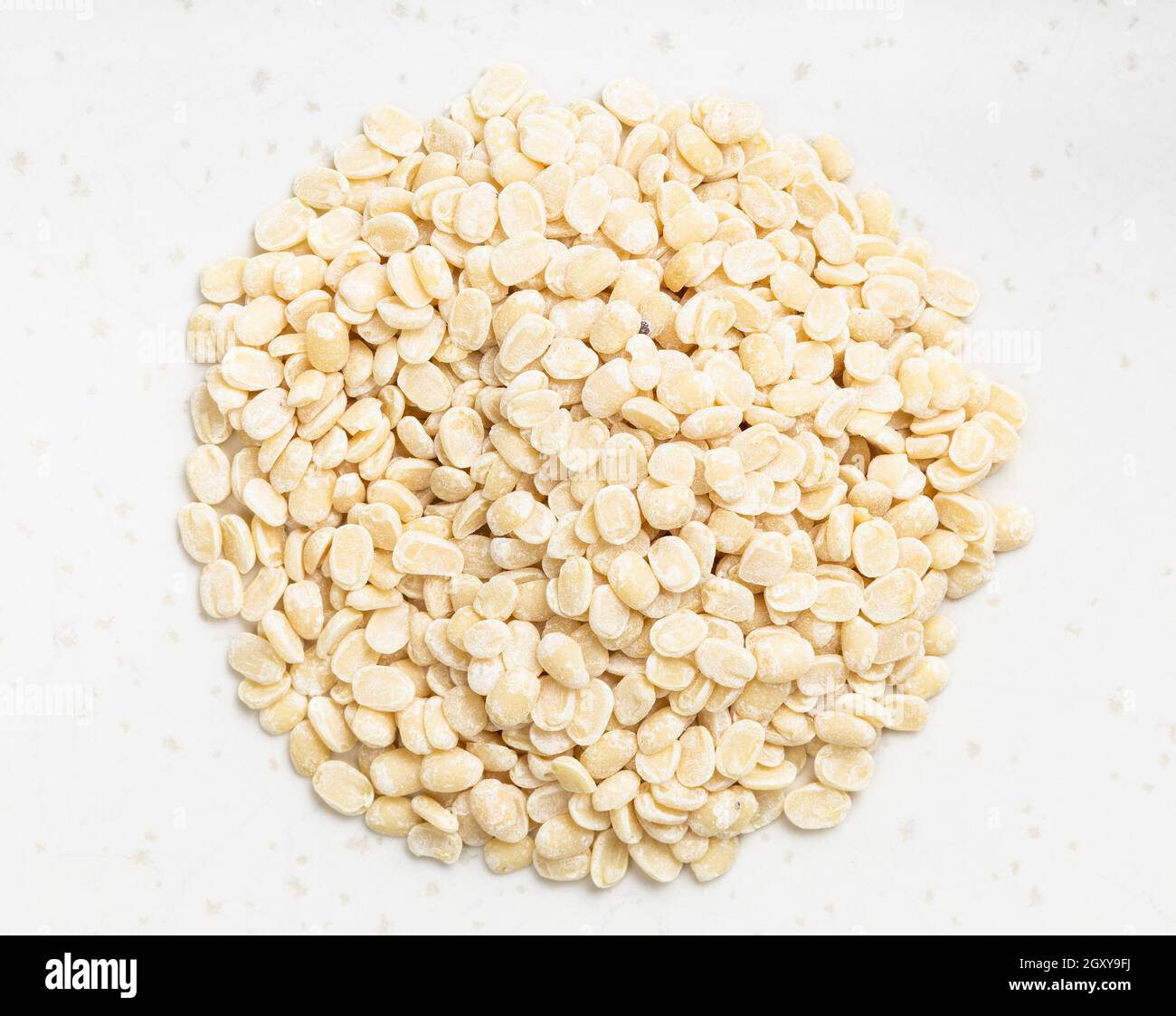 pila di urad dal grezzo (grammo nero diviso) i fagioli si avvicinano alla piastra in ceramica grigia Foto Stock