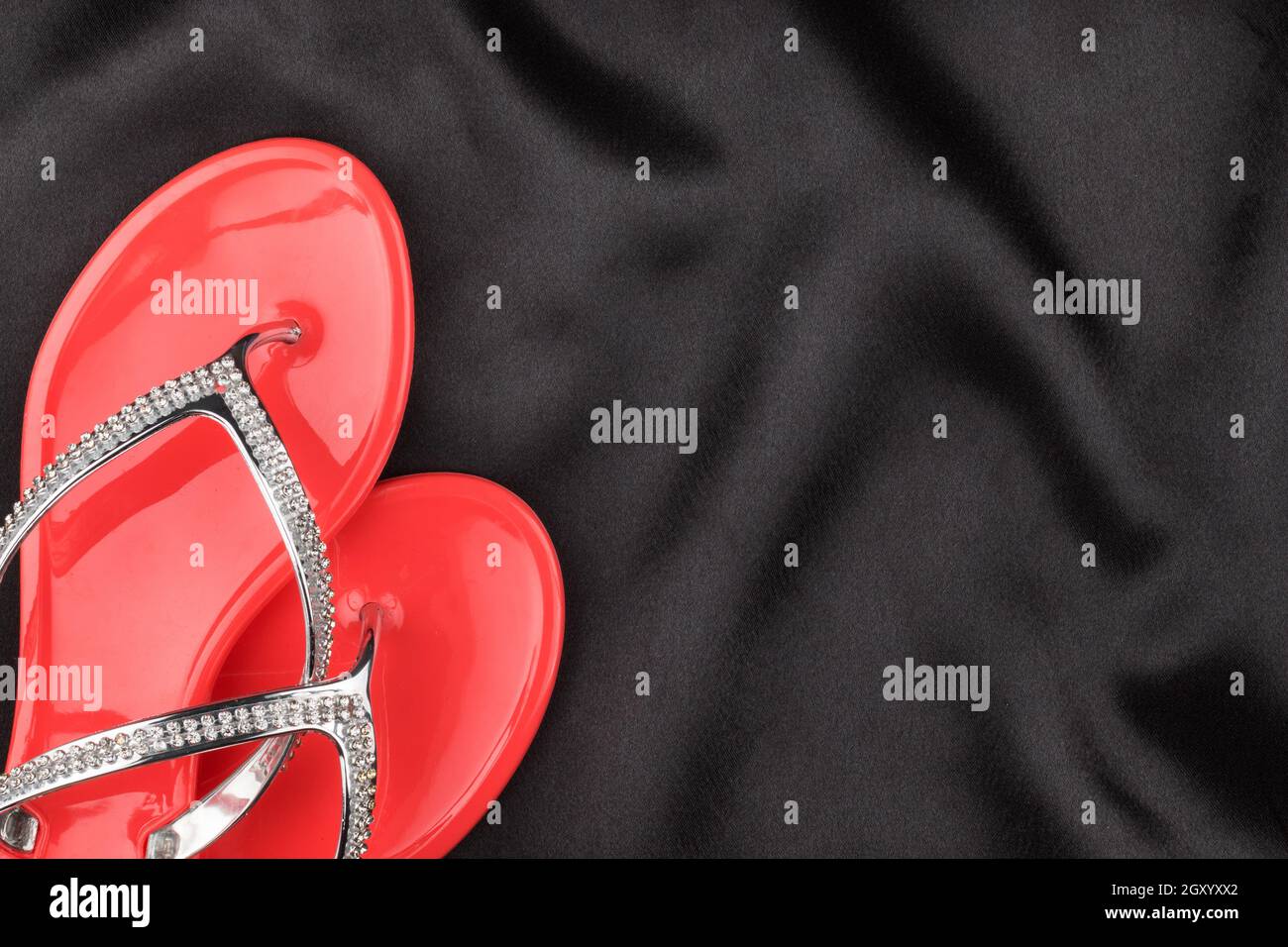 Rosa flip flop decorato con strass giace sul panno nero. Vista da sopra Foto Stock