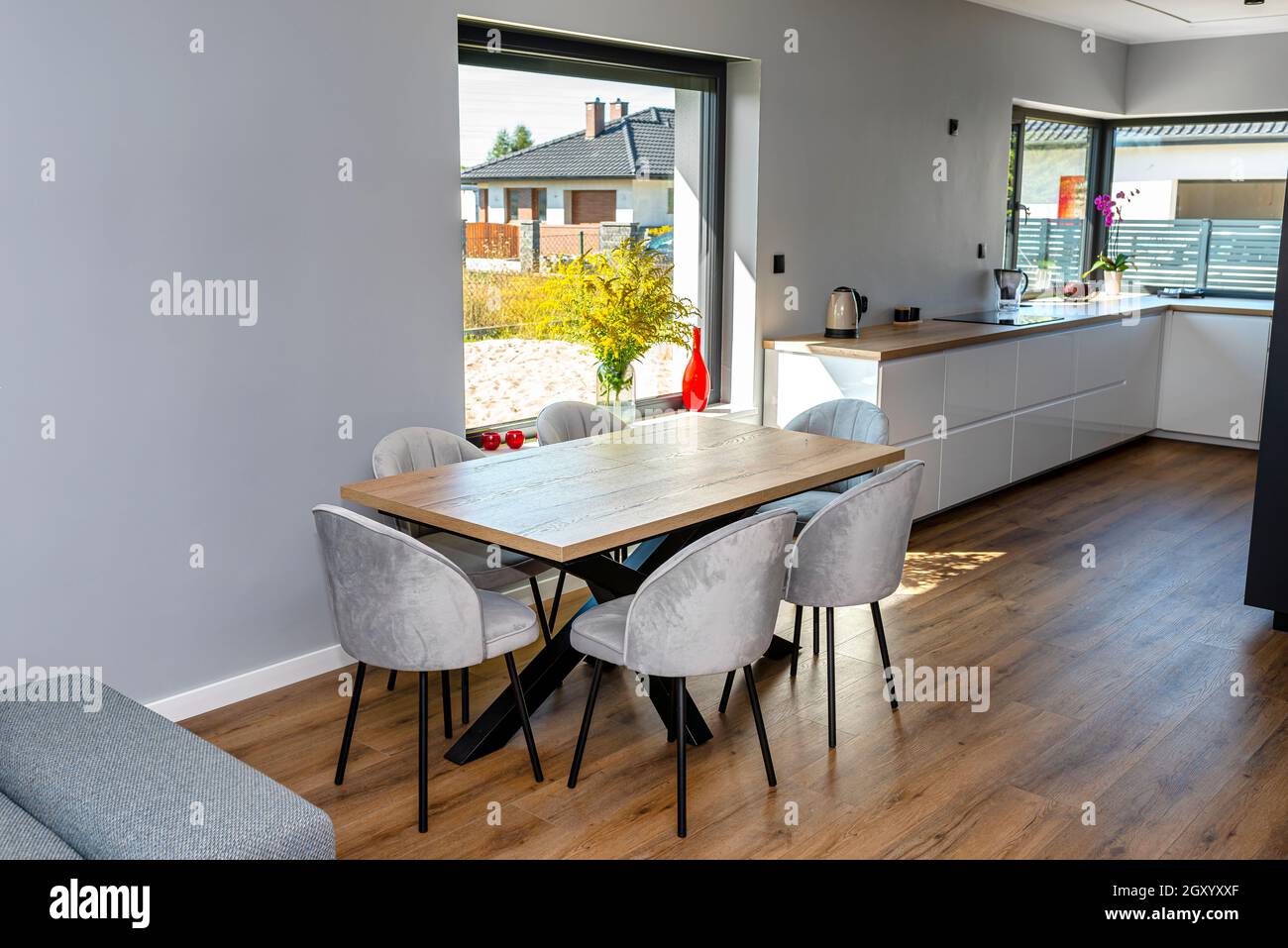 Una moderna sala da pranzo collegata al soggiorno e alla cucina, ci sono grandi finestre nella parete, un tavolo a vista e sedie. Foto Stock