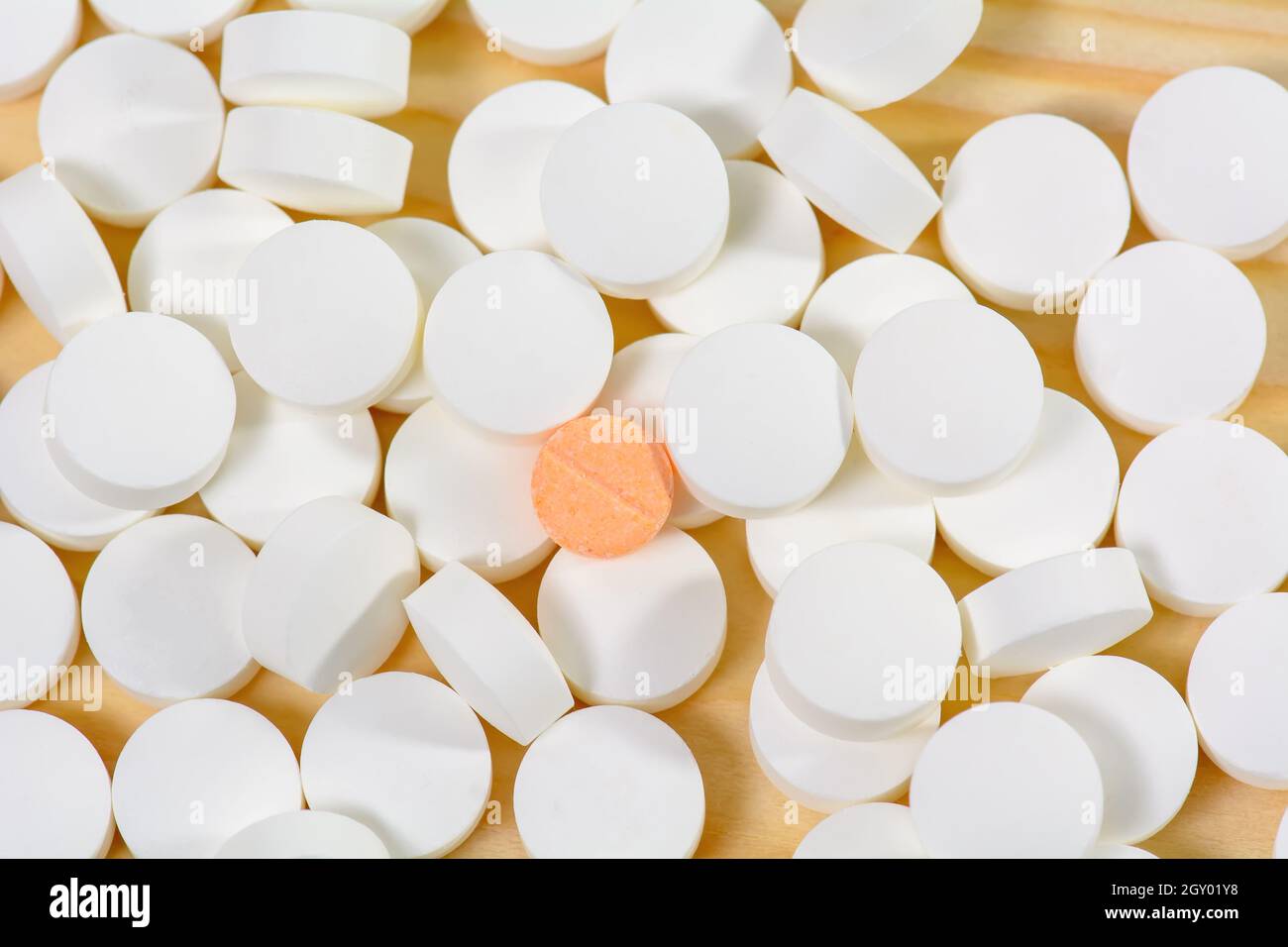 La orange pillole sono su una pila di pillole di bianco su uno sfondo di legno. Foto Stock