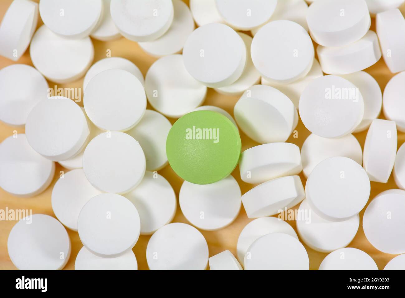 Il verde pillole sono su una pila di pillole di bianco su uno sfondo di legno. Foto Stock