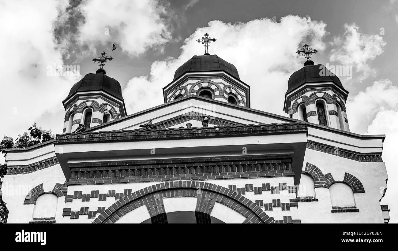 Bianco e nero classica vecchia chiesa ortodossa cristiana rumena con cielo e nuvole Foto Stock