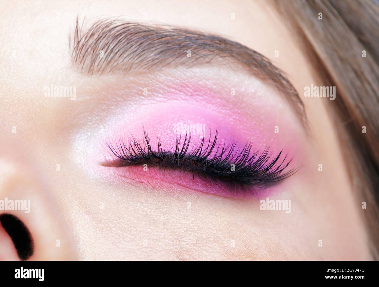 Macro shot closeup dell'occhio femminile chiuso. Donna con naturale sera Vogue viso bellezza trucco. Ragazza con pelle perfetta e occhi rosa ombre. Foto Stock