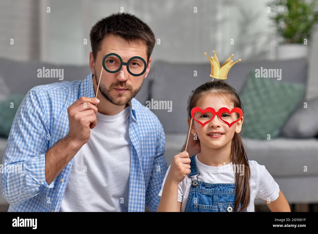 felice padre e bambina che tiene bicchieri di carta sul bastone . Famiglia felice di giocare a casa Foto Stock