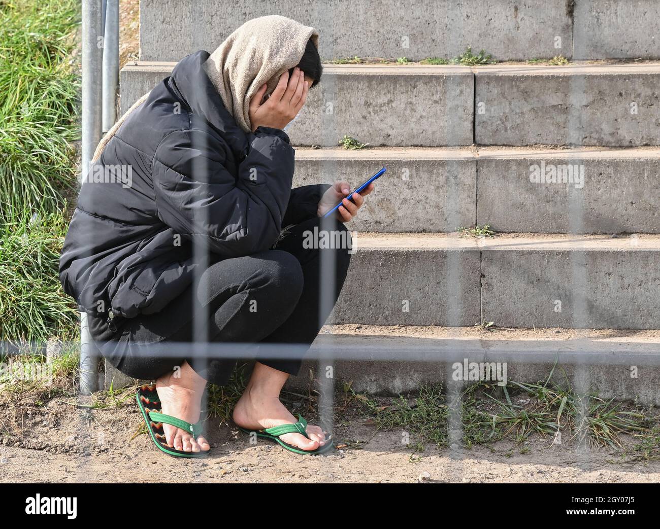 06 ottobre 2021, Brandeburgo, Eisenhüttenstadt: Un migrante siede dietro una recinzione presso il Centro Centrale di accoglienza iniziale per i richiedenti asilo (ZABH) nello stato di Brandeburgo. Nel corso del significativo aumento della registrazione dei migranti a Brandeburgo, il Ministro dell'interno dello Stato di Brandeburgo, Stübgen (CDU), si è informato della situazione attuale in loco. Foto: Patrick Pleul/dpa-Zentralbild/ZB Foto Stock