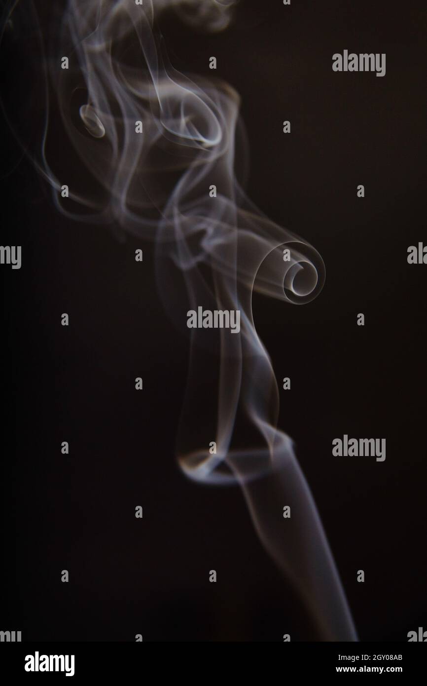 Ricci di fumo bianco e grigio su sfondo nero Foto Stock