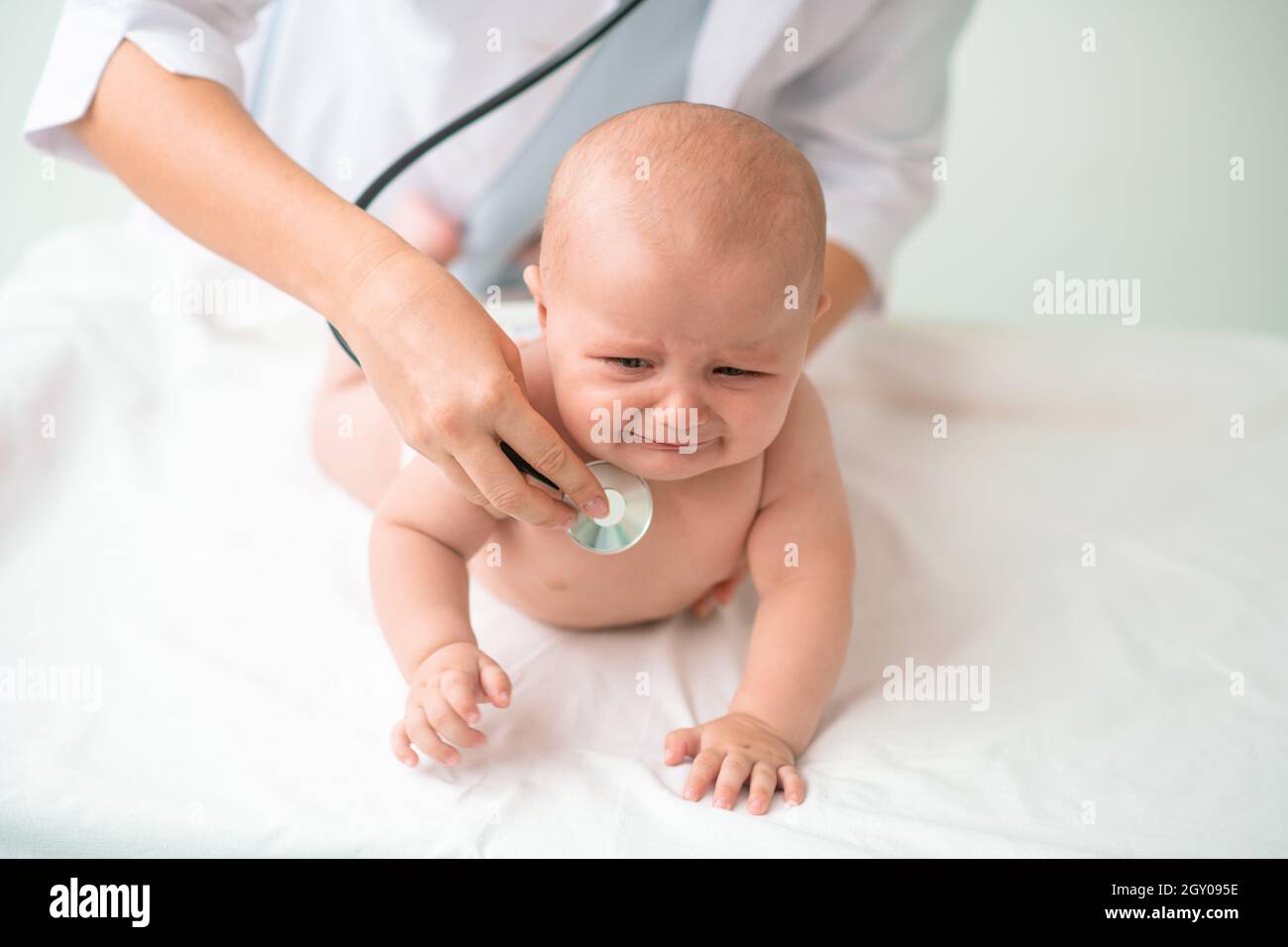 Bambino triste che è esaminato da un medico con uno stetoscopio Foto Stock