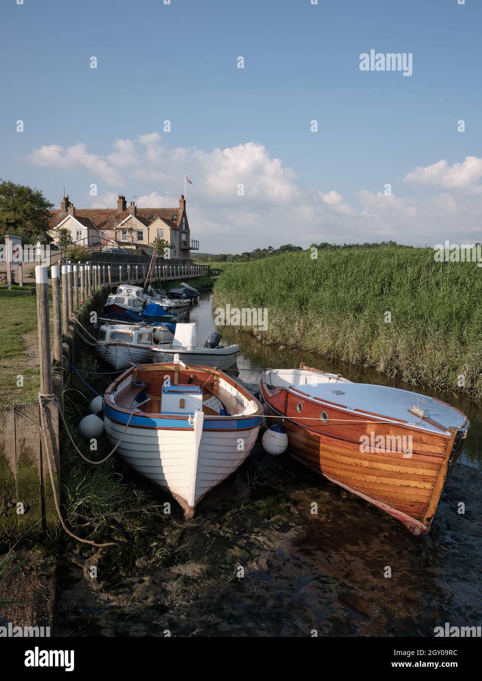 Barche sul piccolo fiume Glaven a bassa marea in Cley accanto al mare e le canne di Cley Marshes Norfolk Heritage Coast Inghilterra UK Foto Stock