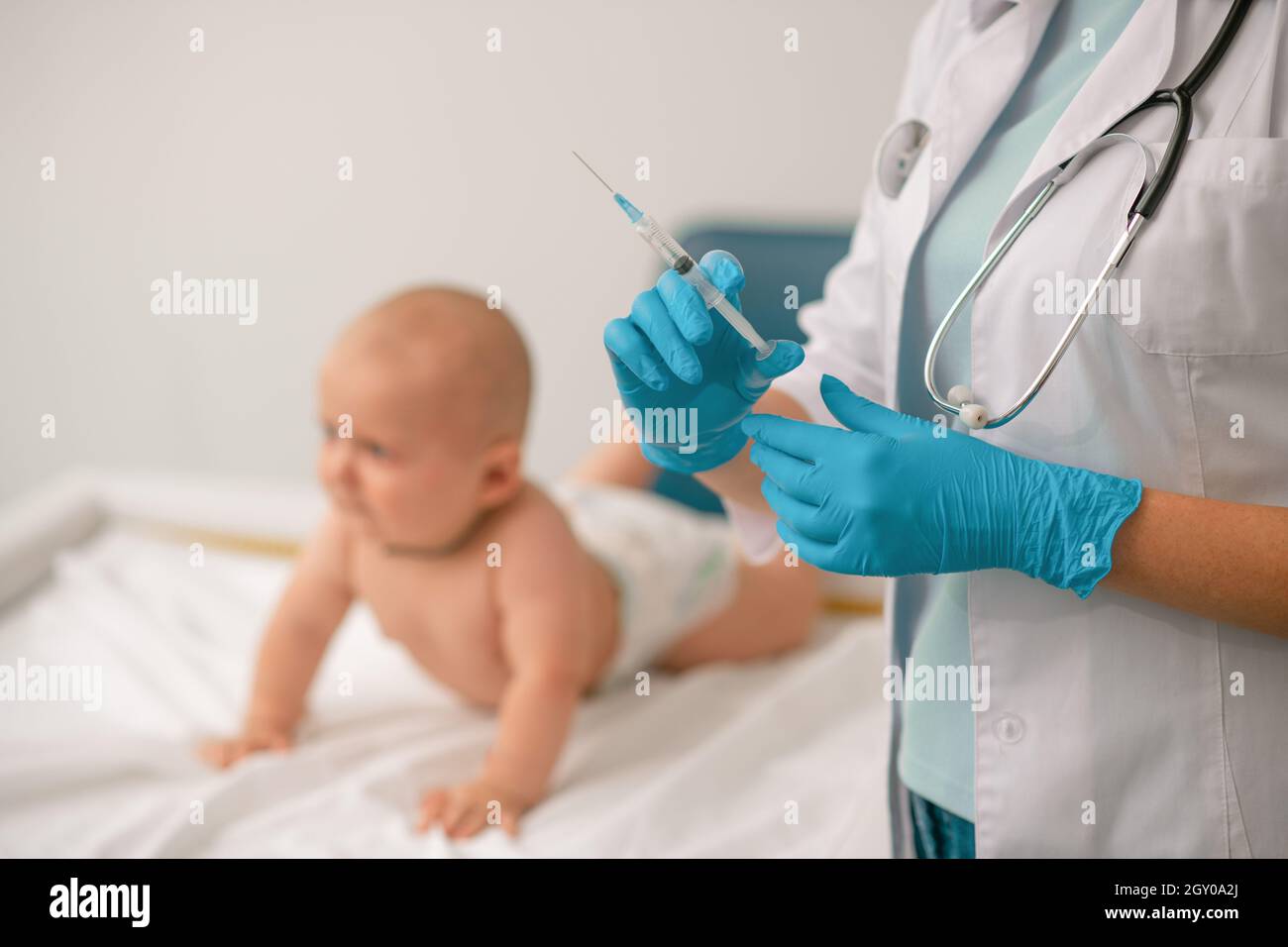 Medico in guanti di nitrile preparazione alla somministrazione di un'iniezione Foto Stock