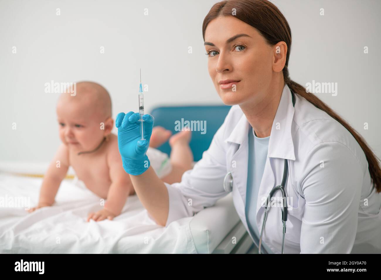 Operatore sanitario che si prepara a somministrare un'iniezione a un neonato Foto Stock