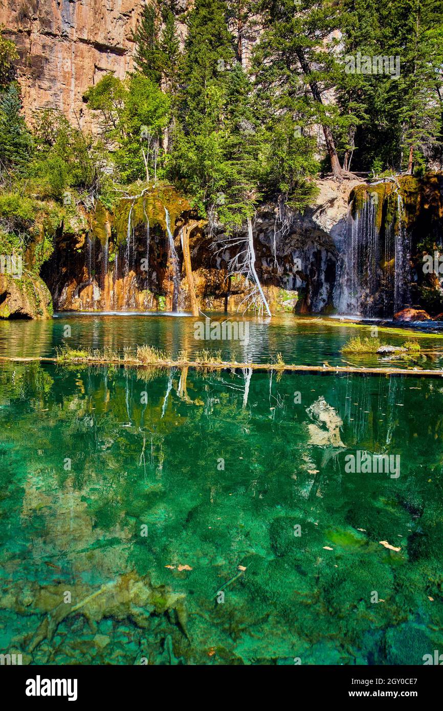 Limpido lago di teal con cascate su rocce di muschio Foto Stock