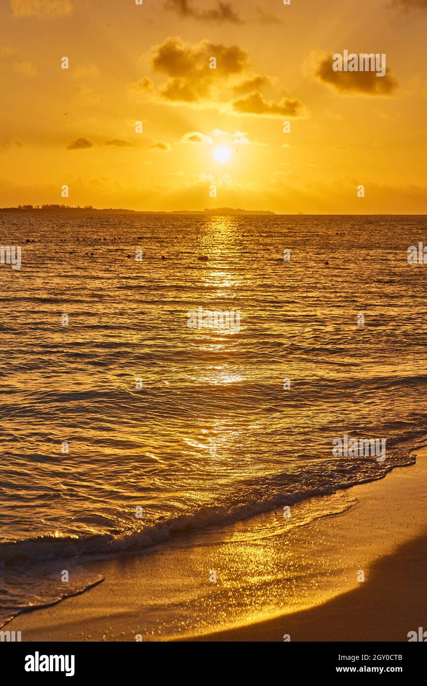 Alba o tramonto sulla spiaggia con onde d'acqua e bagliore dorato Foto Stock