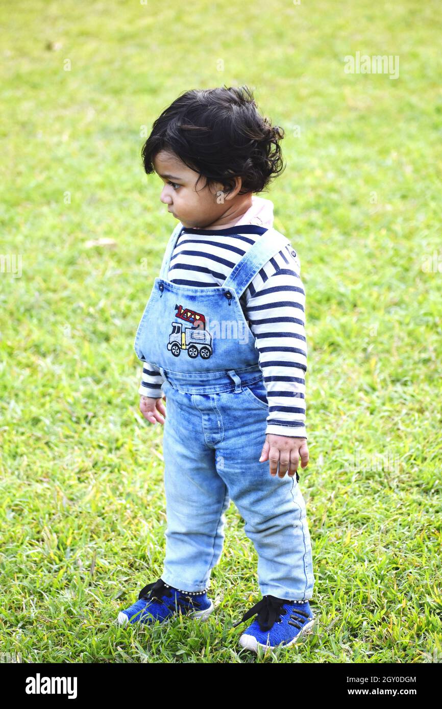 Adorabile bambino indiano con capelli ricci neri che camminano su un campo Foto Stock