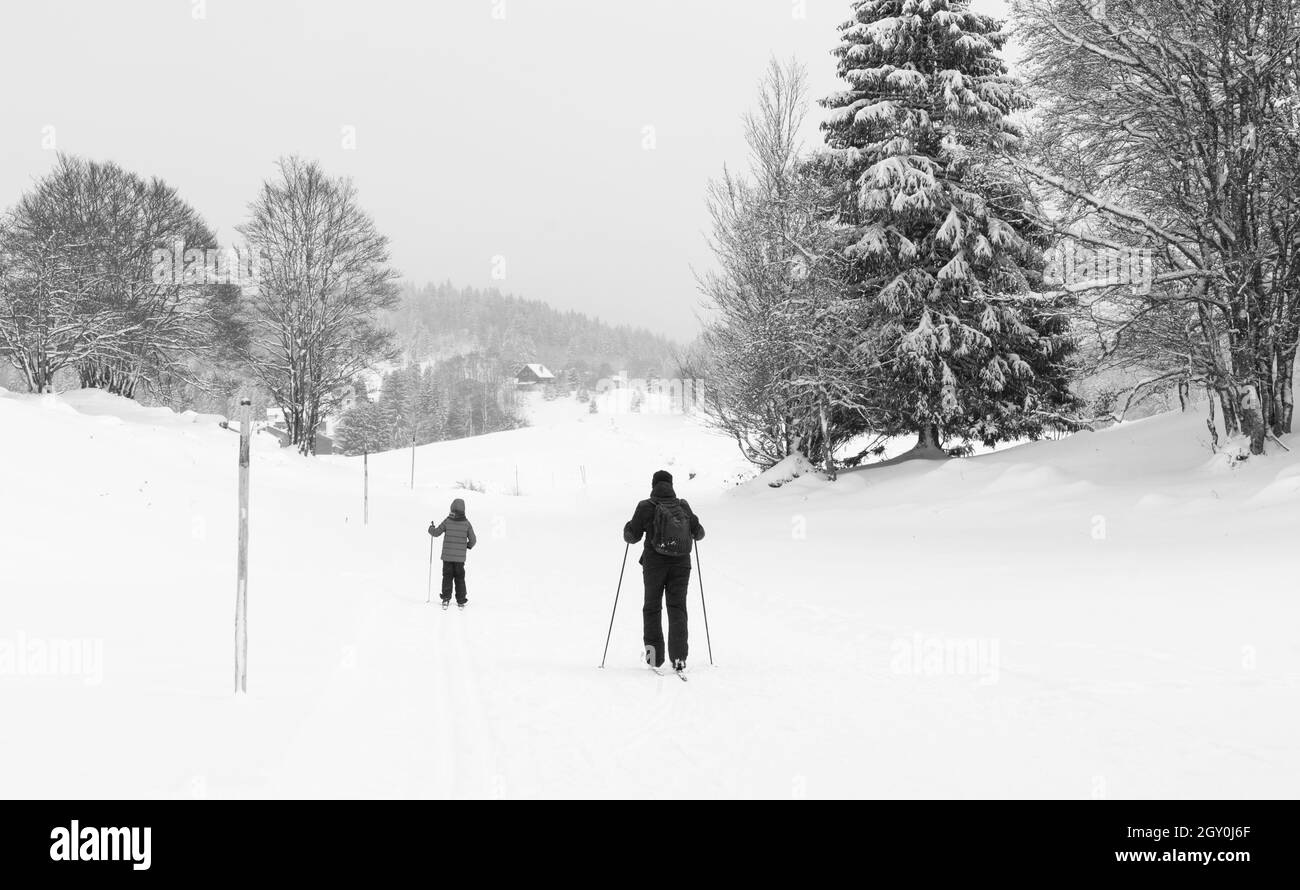 Bambini disabili imparare sci tenendo solo un bastone, incoraggiante da suo padre. Giura, Francia. Foto storica in bianco e nero Foto Stock