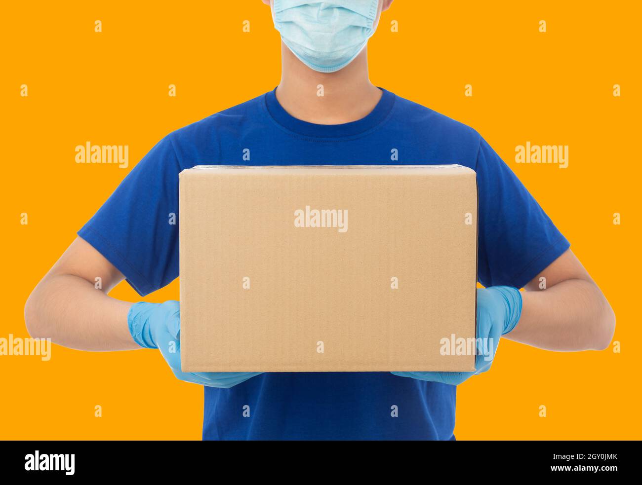 Consegna mano uomo in guanti medici e indossare maschera che tiene cartone scatola mockup modello, Delivery Service Concept. Foto Stock