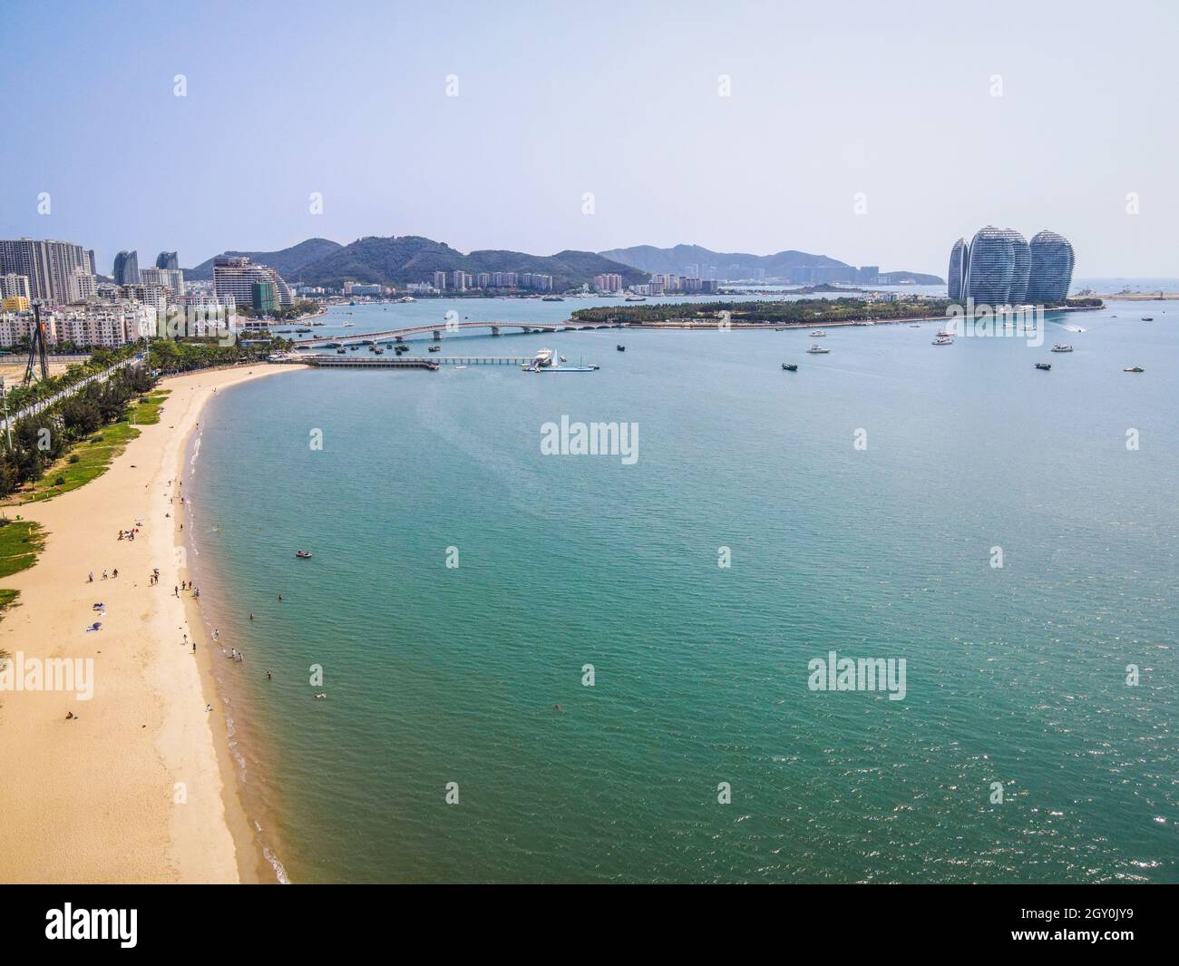 Scatto con droni aerei della spiaggia della baia di Sanya con gente e l'isola di Phoenix sullo sfondo dell'isola di Hainan Cina Foto Stock