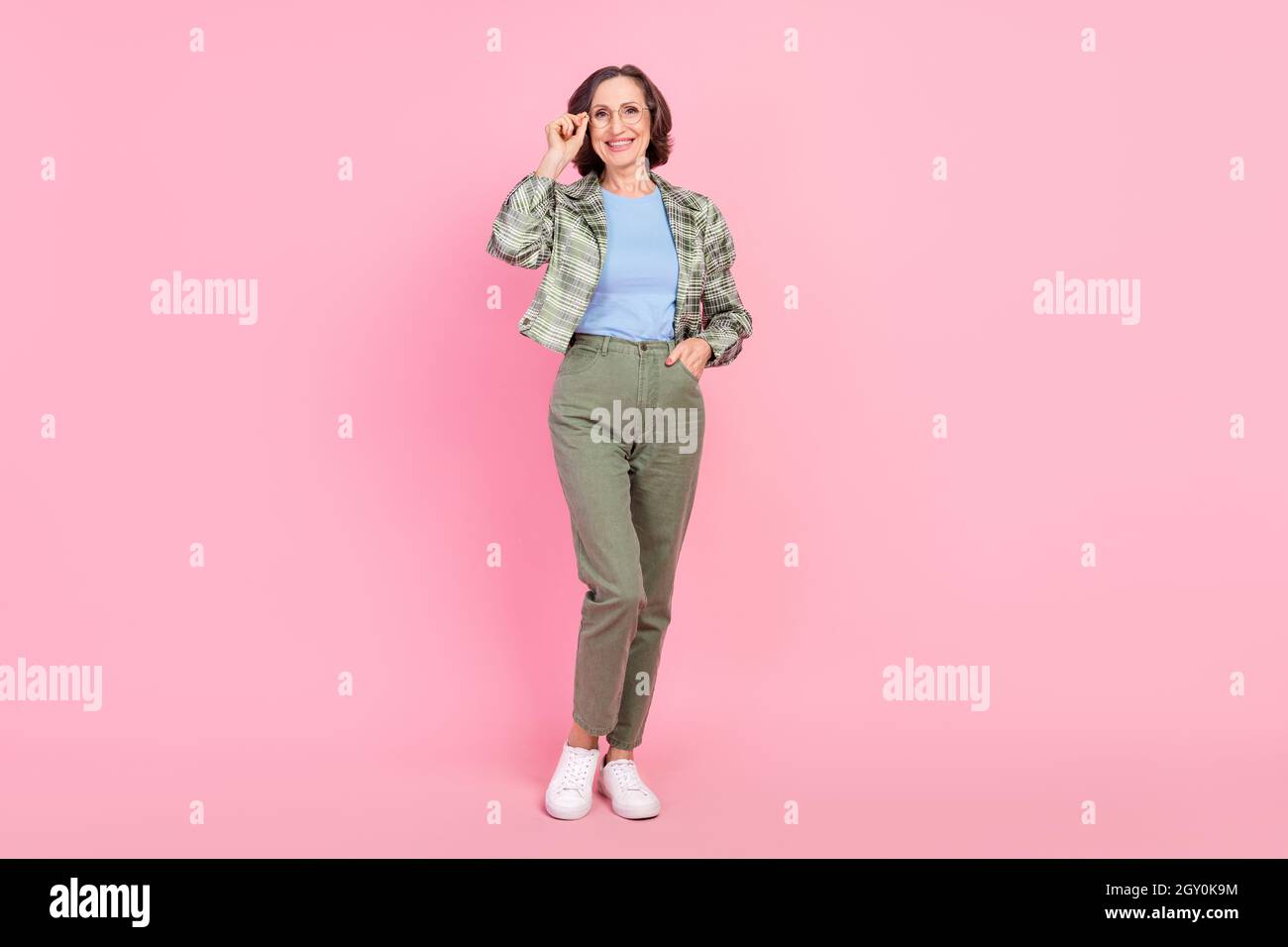 Foto a tutta lunghezza di allegro vecchia donna indossare occhiali vintage abiti di seconda mano isolato su sfondo rosa Foto Stock
